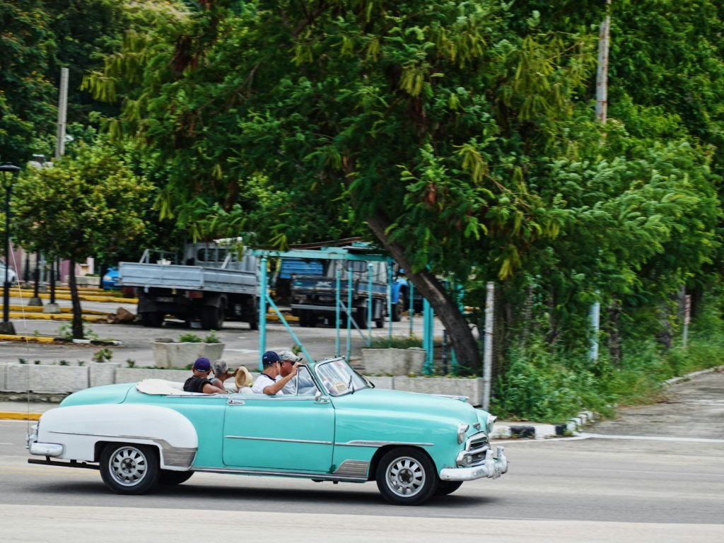 A blue and white car driving down a street